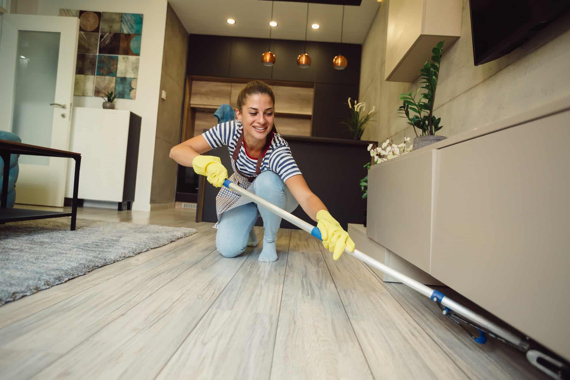 beautiful-young-woman-is-smiling-and-cleaning-floor-under-furniture-at-home-using-a-mop.jpg